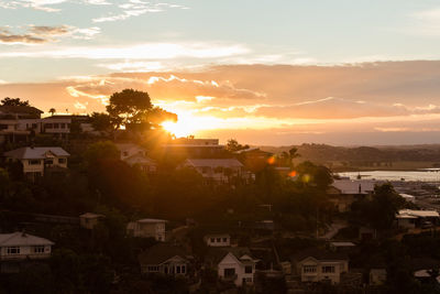 Houses in city against sky during sunset