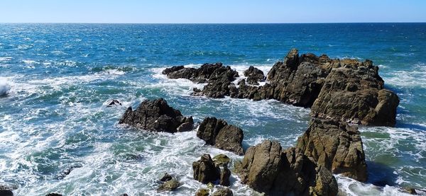 Scenic view of rocks in sea against sky