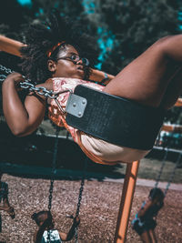 Side view of girl swinging at playground during sunny day