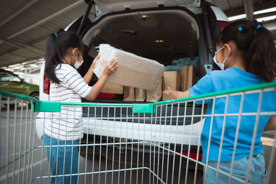 Girls putting grocery in car trunk