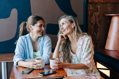 Portrait of smiling friends sitting on table