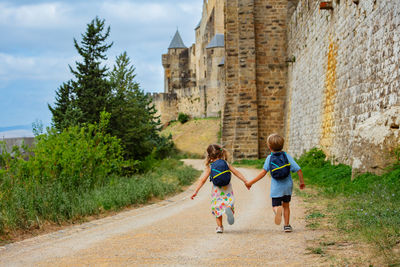 Rear view of siblings walking on road