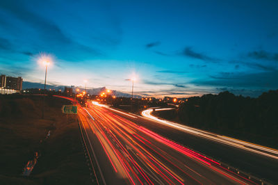 Light trails on road in city against sky at night