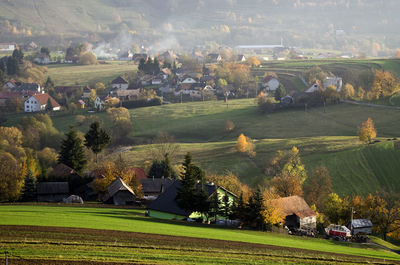 Scenic view of field and houses against trees