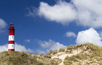 The photo shows the amrum lighthouse in the dunes with beautiful sky