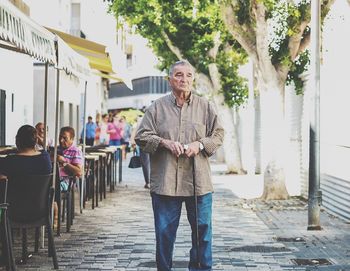 Senior man looking away while standing on street