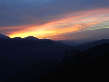 Scenic view of silhouette mountains against orange sky