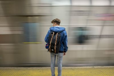 Rear view of man standing on train at railroad station