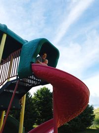 Low angle view of child in playground against sky