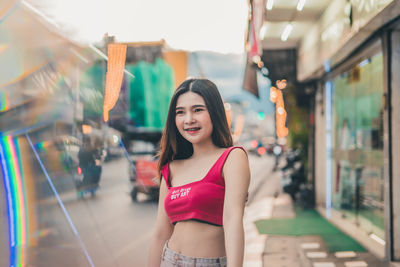 Smiling young woman looking away while standing in city