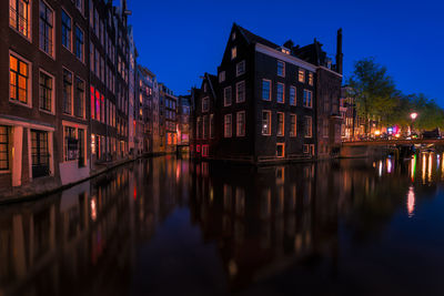 Canal amidst buildings at night