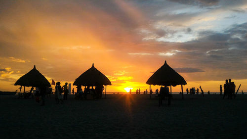 Silhouette people on beach against sky during sunset