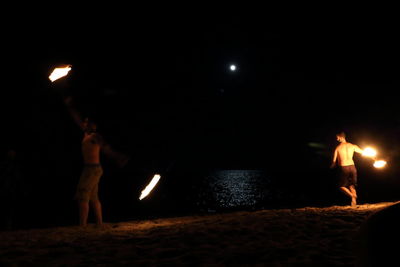 People standing on beach against sky at night