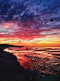 Scenic view of sea against dramatic sky during sunset