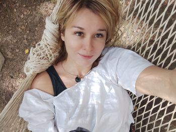 Portrait of a beautiful young woman . blonde girl in a white t-shirt in a hammock