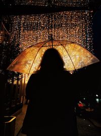 Rear view of silhouette woman standing at night