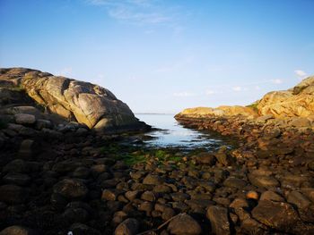 Rocks on shore by sea against sky