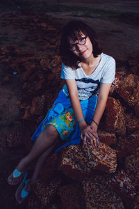 High angle view of young woman sitting on rock