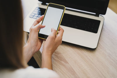 Midsection of woman using mobile phone on table