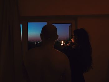 Rear view of silhouette couple sitting at window