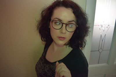 Portrait of beautiful young woman standing against wall