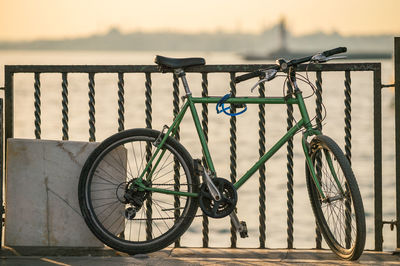 Bicycle parked by railing on promenade