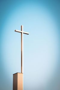 Low angle view of cross on building against blue sky