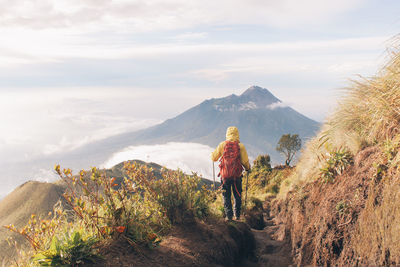 Rear view of people walking on mountain against sky