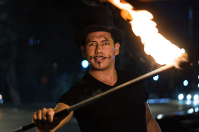 Portrait of man performing with fire on street at night