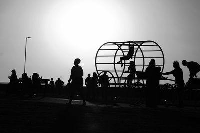 Silhouette people playing soccer against sky