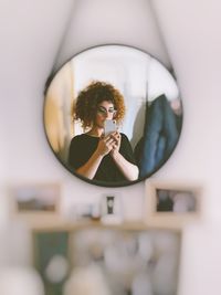 Portrait of young woman photographing through smart phone