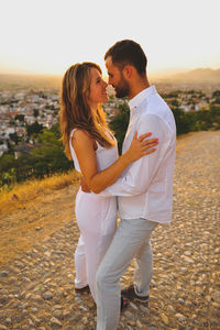 Young couple looking each other face to face while standing in city at sunset