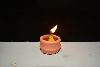 Close-up of illuminated burning candle against black background