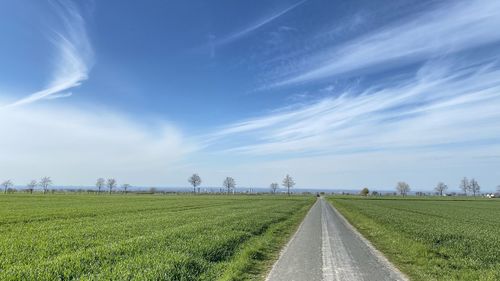 Road amidst field against sky