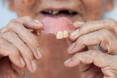 Cropped image of senior woman holding dentures