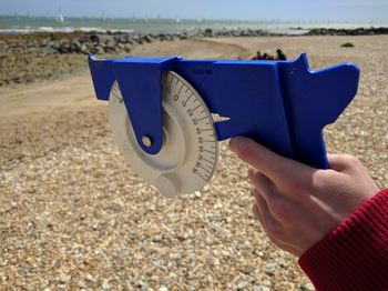 Cropped hand holding clinometer at beach