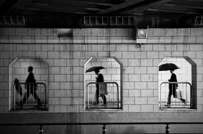 Men walking on walkway under bridge