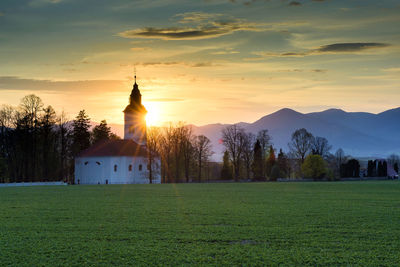 Traditional church on field against sky during sunset