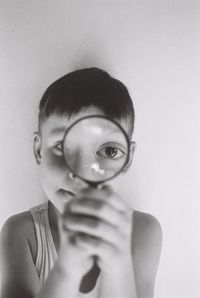 Portrait of boy holding camera over white background