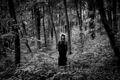 Full length of woman standing on tree trunk in forest