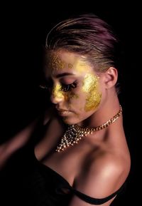 Close-up of young woman with face paint over black background