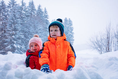 Portrait of cute girl sitting on snow covered field