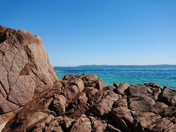 Rock formation on beach against clear blue sky