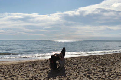 Man relaxing on beach against sky