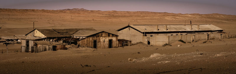 Exterior of abandoned house on desert against sky