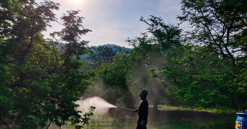 Man standing by waterfall in forest