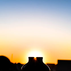 Silhouette structures against clear sky at sunset