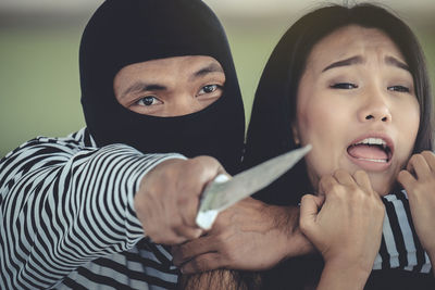 Cropped image of criminal holding knife by frightened woman