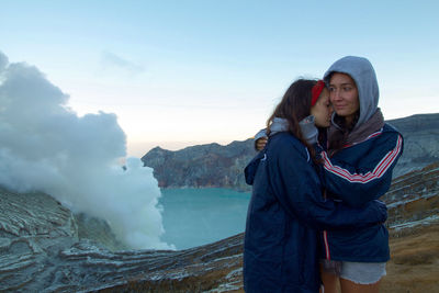 Sisters embracing against volcanic mountain