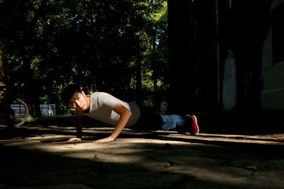 Young woman looking away while sitting on tree